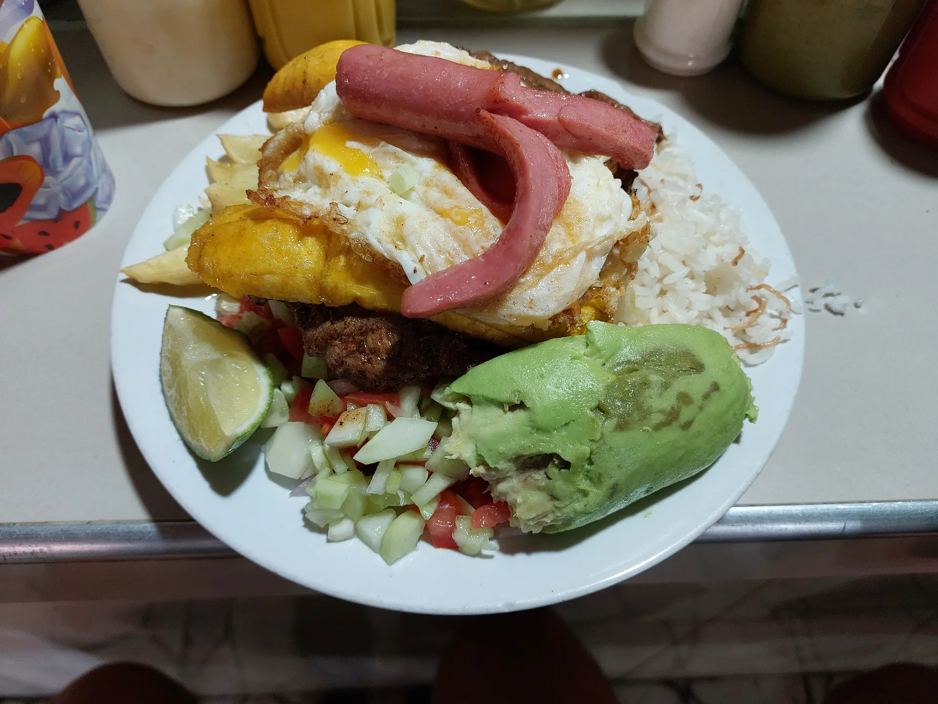 Loaded Peruvian comfort plate with steak, fried egg, plantain, rice, fries, salsa criolla, and avocado.